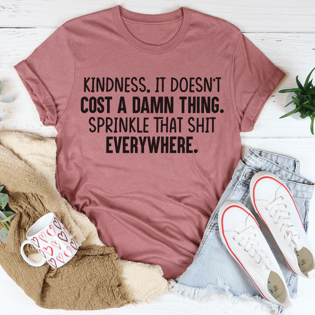 A stylish black t-shirt with the phrase 'Kindness Doesn't Cost A Damn Thing' printed in white, showcasing its soft fabric and durable stitching.