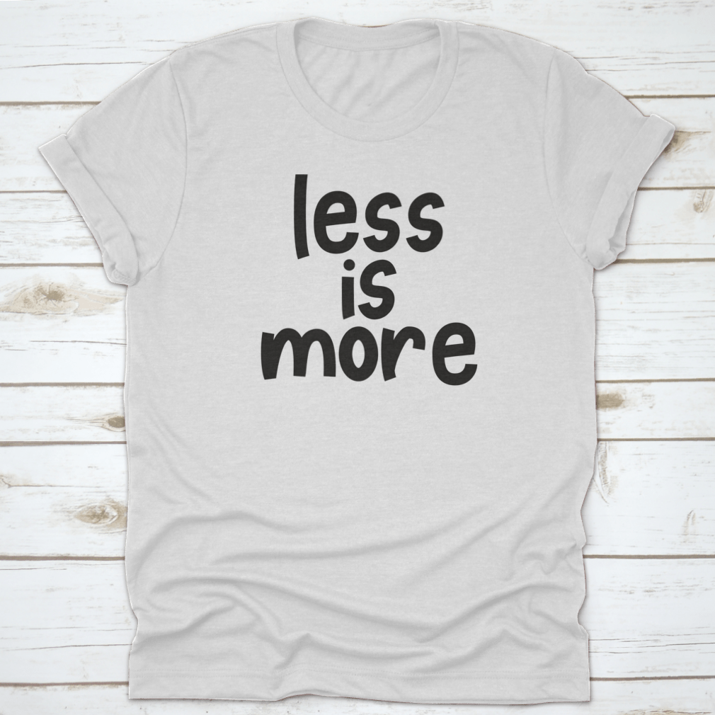 A stylish grey T-shirt featuring the hand-lettered slogan 'Less Is More', promoting zero waste and sustainable fashion.