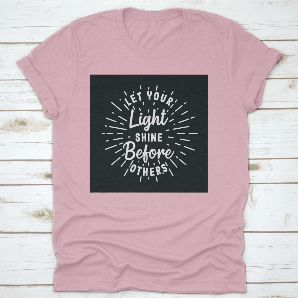 A comfortable hand-lettered typography shirt with the phrase 'Let Your Light Shine Before Others' displayed prominently.