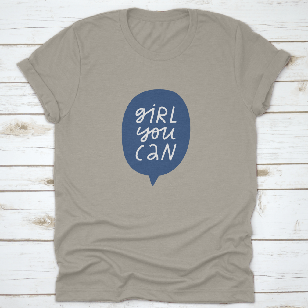 A stylish t-shirt featuring minimalist hand-drawn lettering in a blue speech bubble that reads 'Girl You Can', showcasing a casual and empowering design.