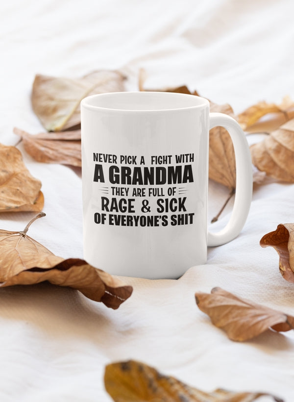 A humorous ceramic mug with the phrase 'Never Pick A Fight With A Grandma' printed on it, featuring a glossy finish and sturdy handle.
