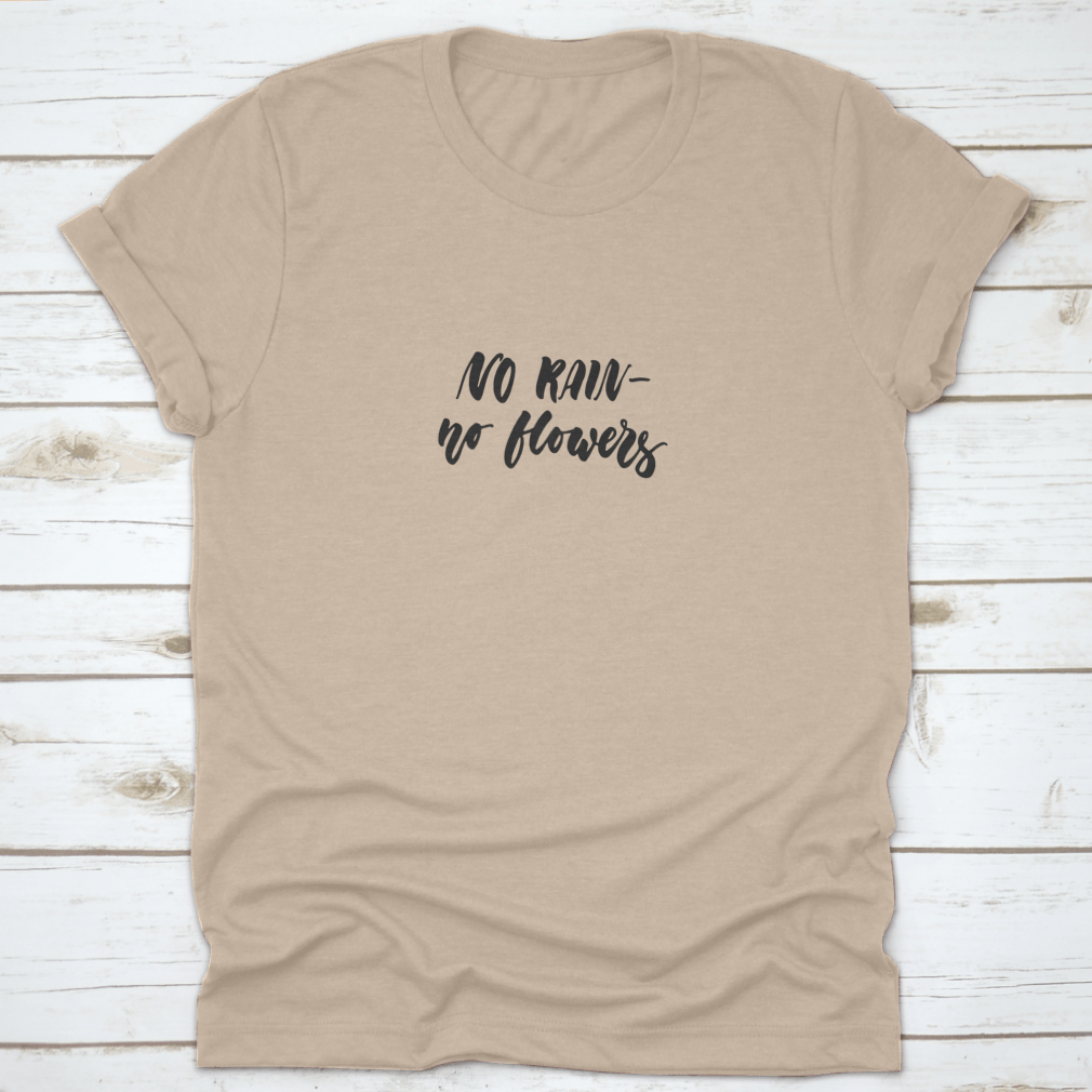 A stylish t-shirt featuring the hand-drawn lettering phrase 'No Rain - No Flowers' on a soft cotton fabric, showcasing a positive message.