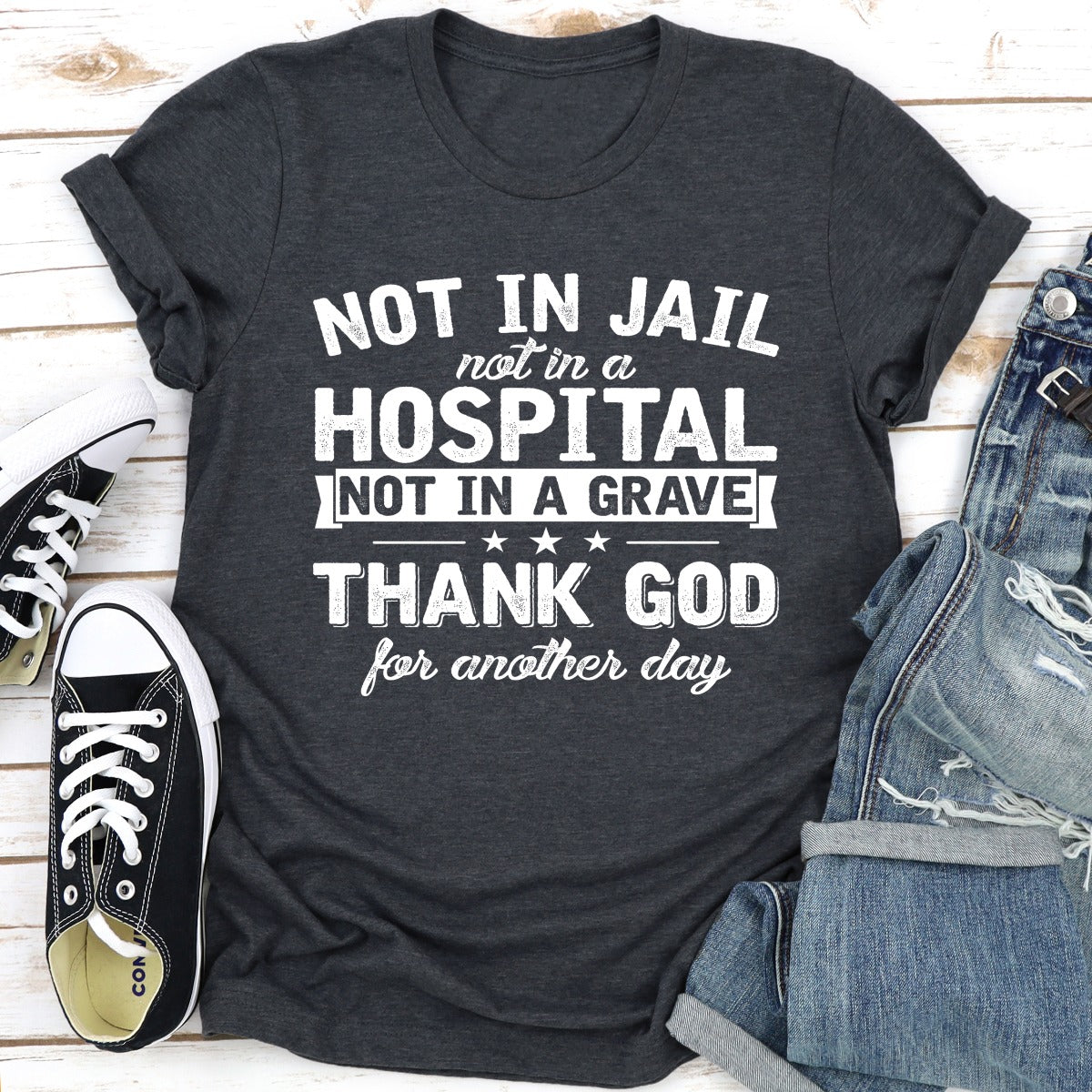 A stylish black t-shirt with the phrase 'Not In Jail Not In A Hospital Not In A Grave' printed on it, showcasing its soft fabric and durable stitching.