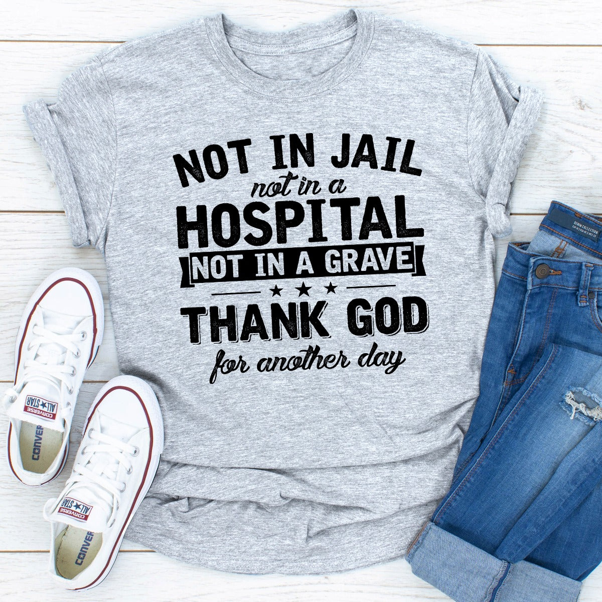 A stylish black t-shirt with the phrase 'Not In Jail Not In A Hospital Not In A Grave' printed on it, showcasing its soft fabric and durable stitching.