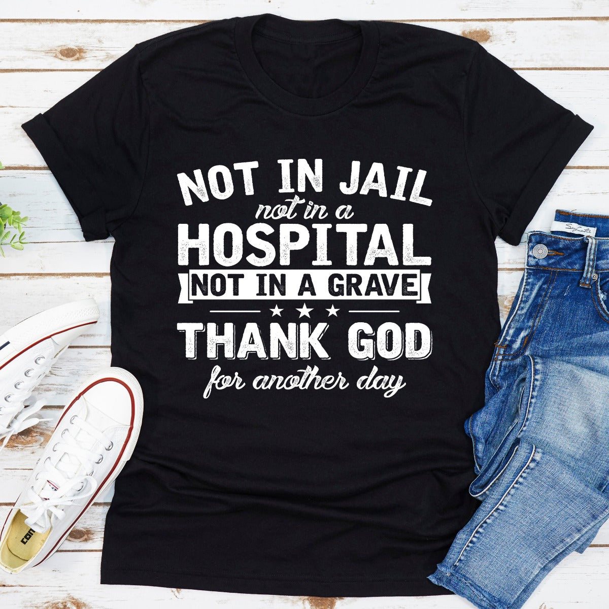 A stylish black t-shirt with the phrase 'Not In Jail Not In A Hospital Not In A Grave' printed on it, showcasing its soft fabric and durable stitching.