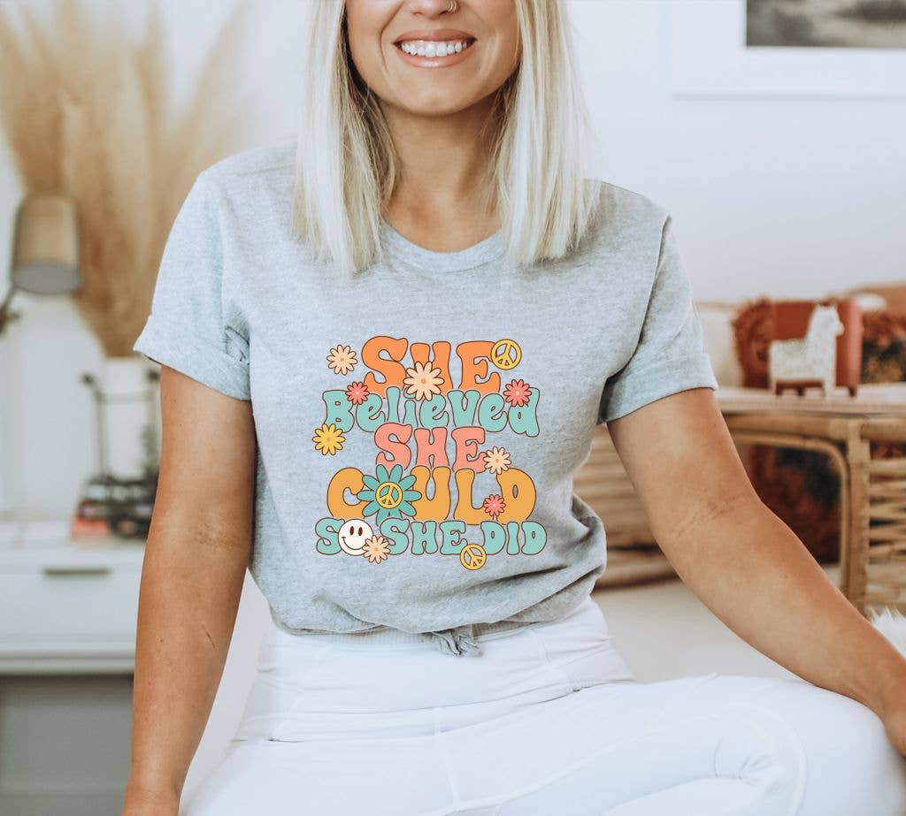 A stylish black T-shirt featuring the inspirational quote 'She Believed She Could So She Did' printed in elegant typography.