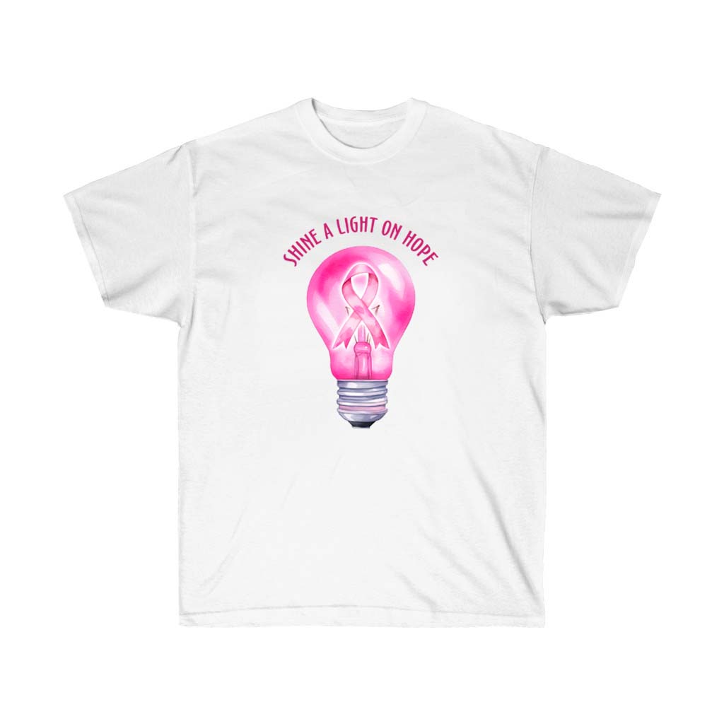 A unisex pink t-shirt with the phrase 'Shine a Light on Hope' printed on it, symbolizing breast cancer awareness.