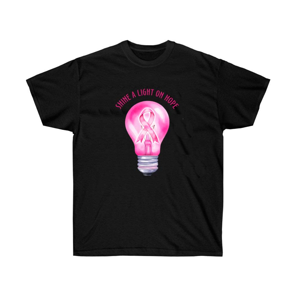 A unisex pink t-shirt with the phrase 'Shine a Light on Hope' printed on it, symbolizing breast cancer awareness.