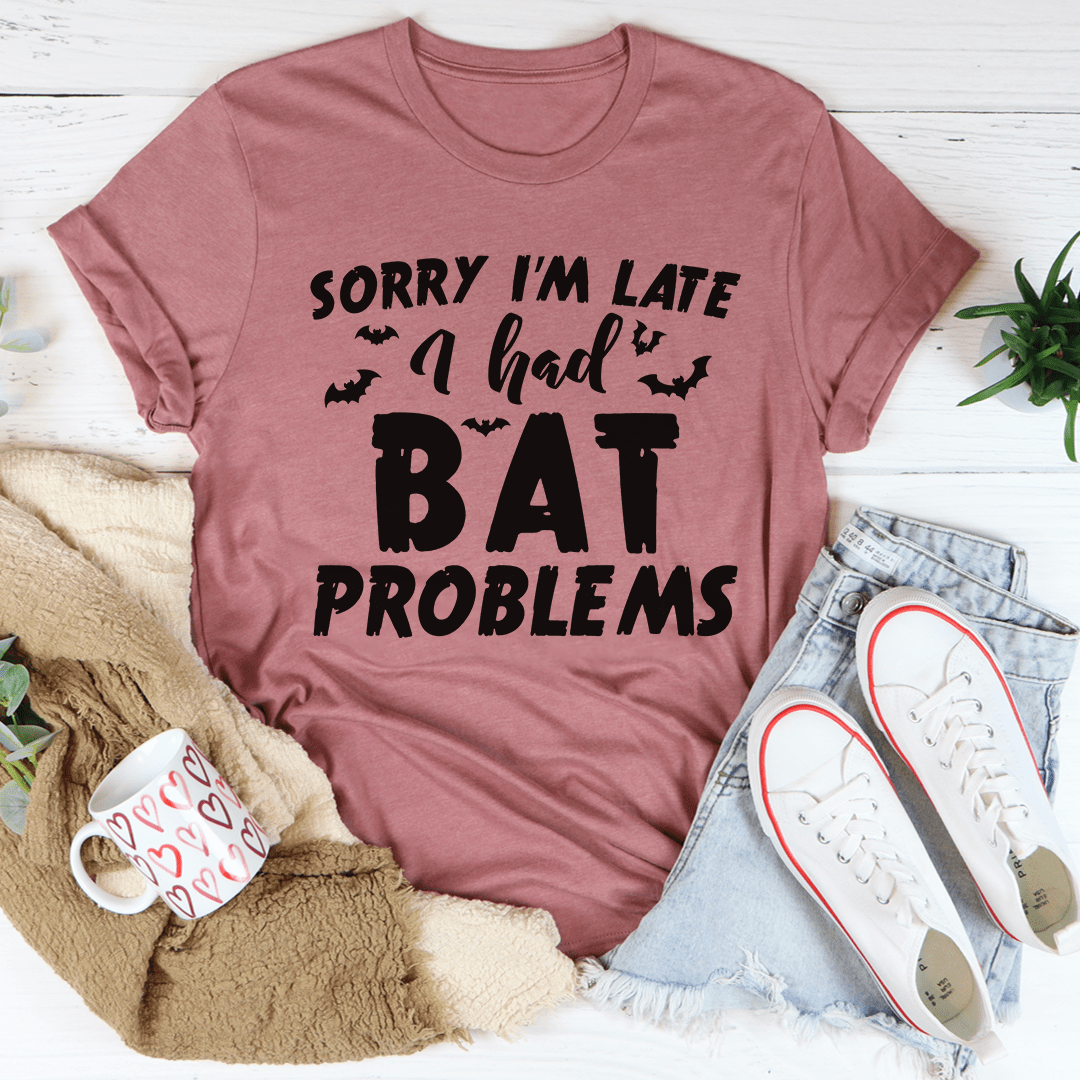 A black Halloween tee featuring the phrase 'Sorry I'm Late I Had Bat Problems' in vibrant colors, made from 100% soft cotton.