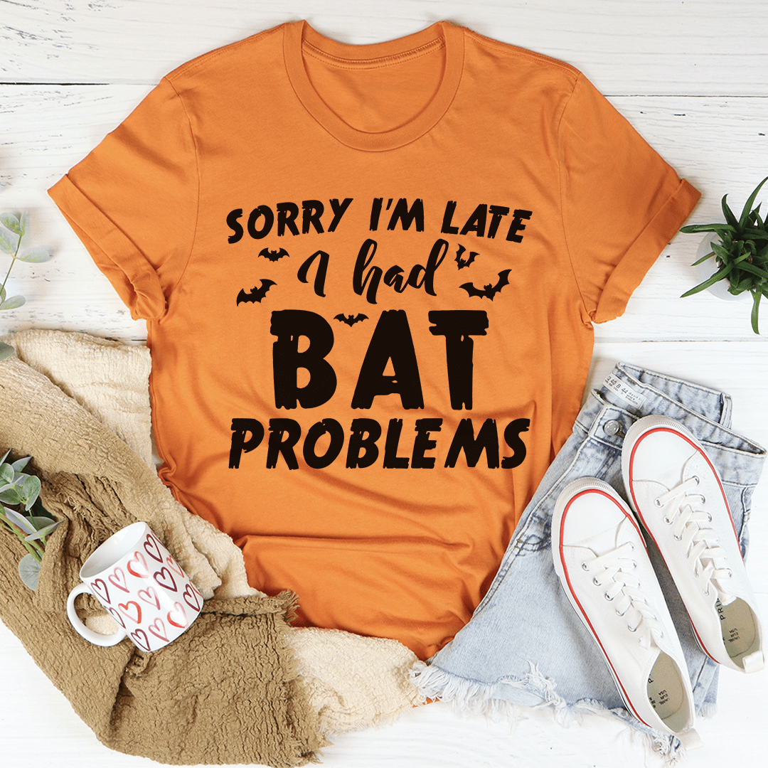 A black Halloween tee featuring the phrase 'Sorry I'm Late I Had Bat Problems' in vibrant colors, made from 100% soft cotton.