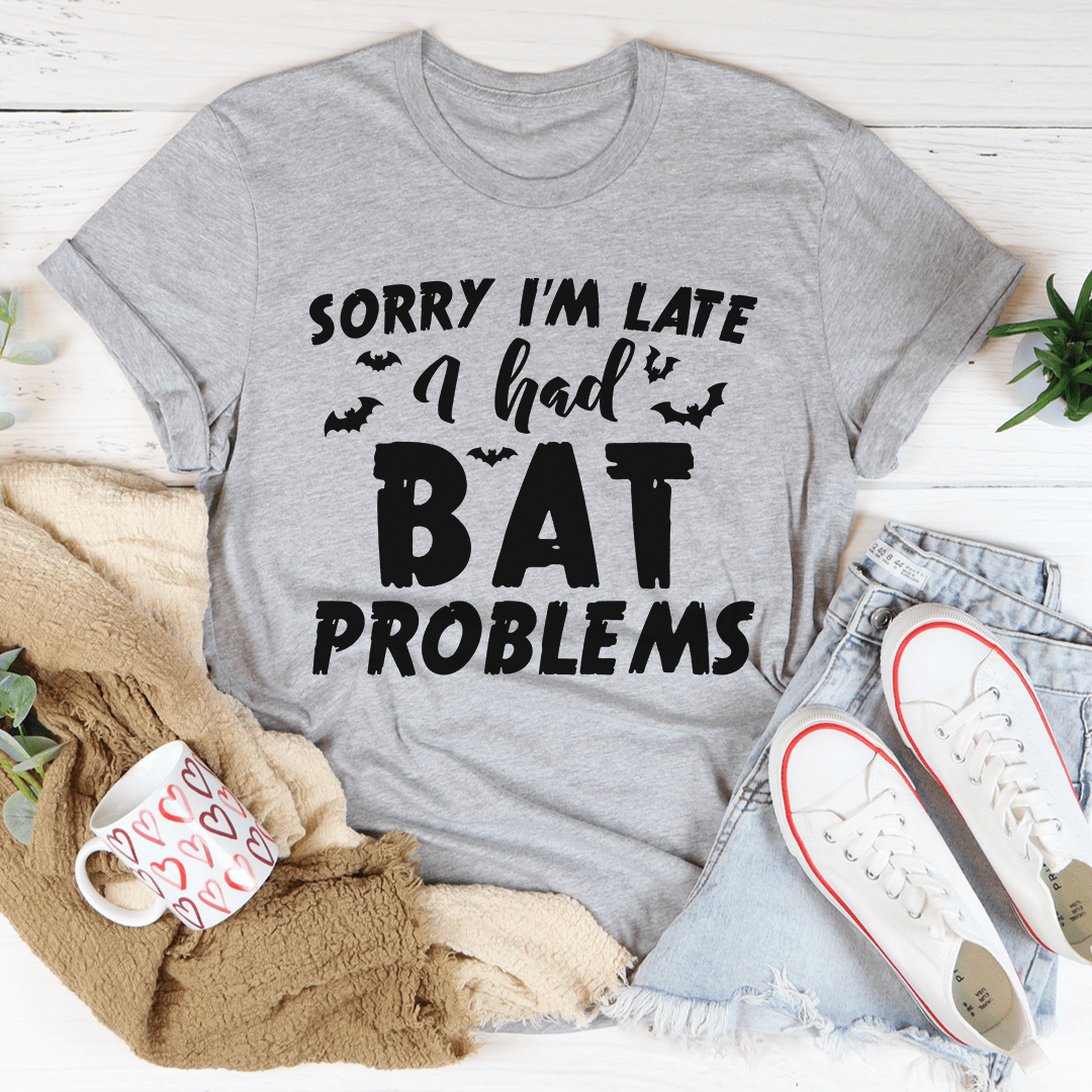 A black Halloween tee featuring the phrase 'Sorry I'm Late I Had Bat Problems' in vibrant colors, made from 100% soft cotton.