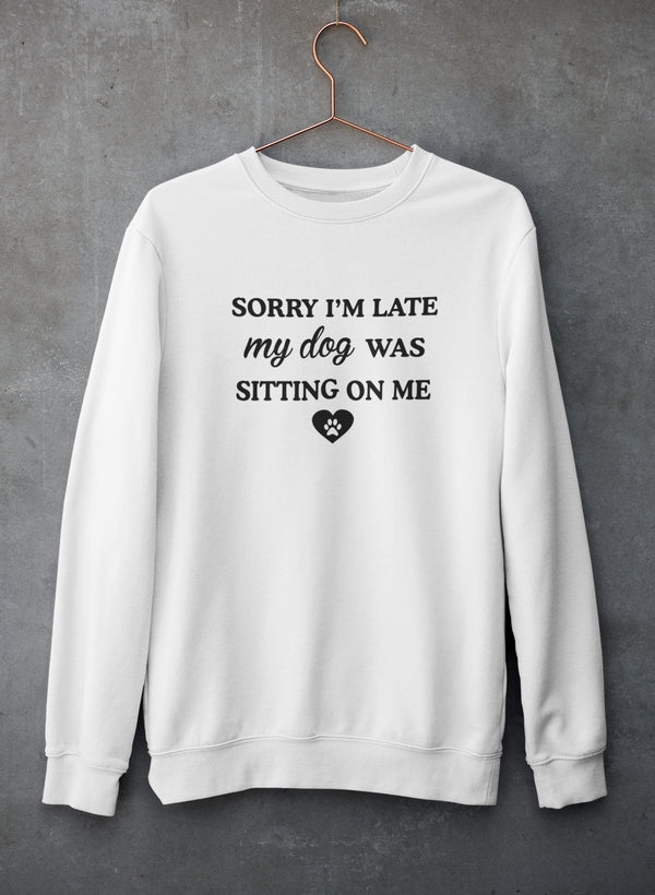 A cozy sweatshirt featuring the phrase 'Sorry I'm Late My Dog Was Sitting On Me' in a playful font, perfect for dog lovers.