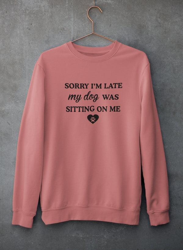 A cozy sweatshirt featuring the phrase 'Sorry I'm Late My Dog Was Sitting On Me' in a playful font, perfect for dog lovers.
