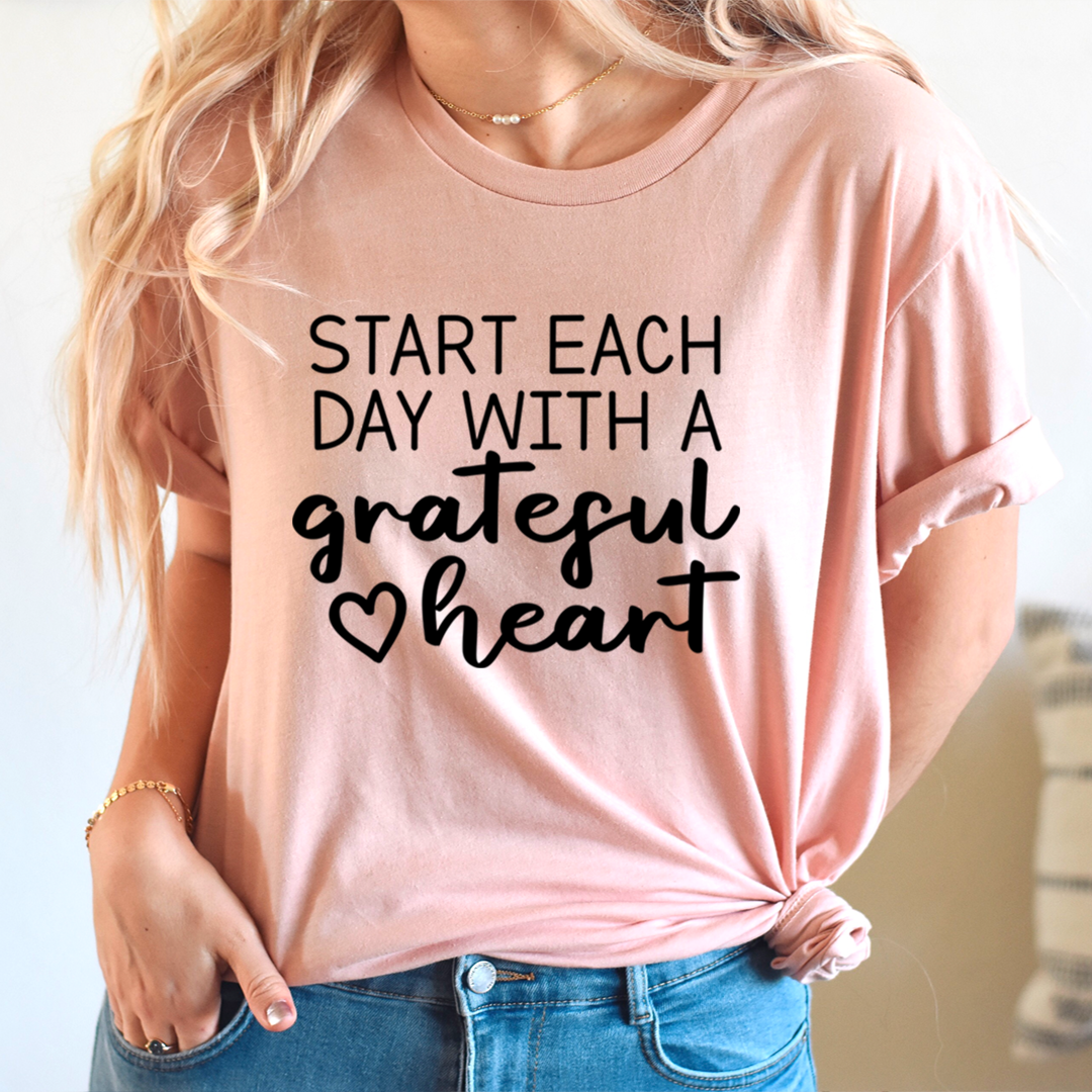 A soft, durable t-shirt featuring the phrase 'Start Each Day With A Grateful Heart' in vibrant print, perfect for everyday wear.