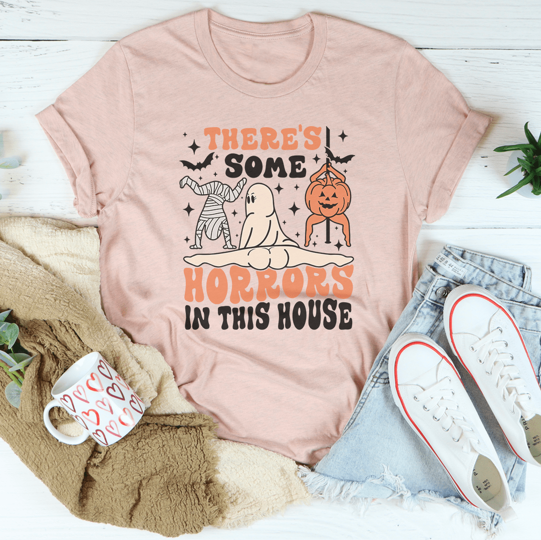 A black Halloween tee featuring the phrase 'There's Some Horrors In This House' in spooky font, made from 100% soft cotton.