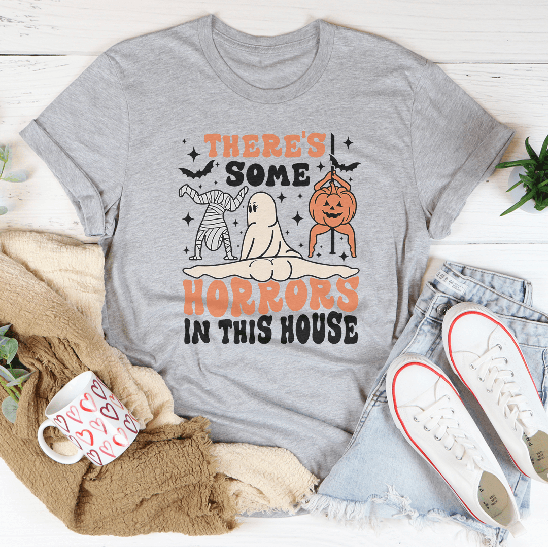A black Halloween tee featuring the phrase 'There's Some Horrors In This House' in spooky font, made from 100% soft cotton.