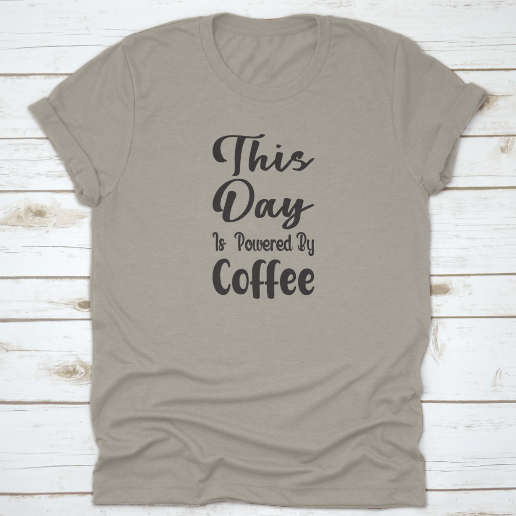 A stylish cotton t-shirt featuring the quote 'This Day Is Powered By Coffee' in a modern font, perfect for coffee lovers.