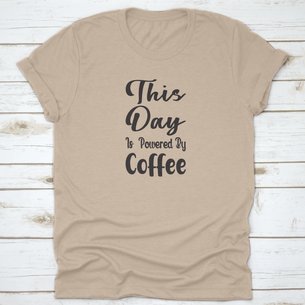 A stylish cotton t-shirt featuring the quote 'This Day Is Powered By Coffee' in a modern font, perfect for coffee lovers.