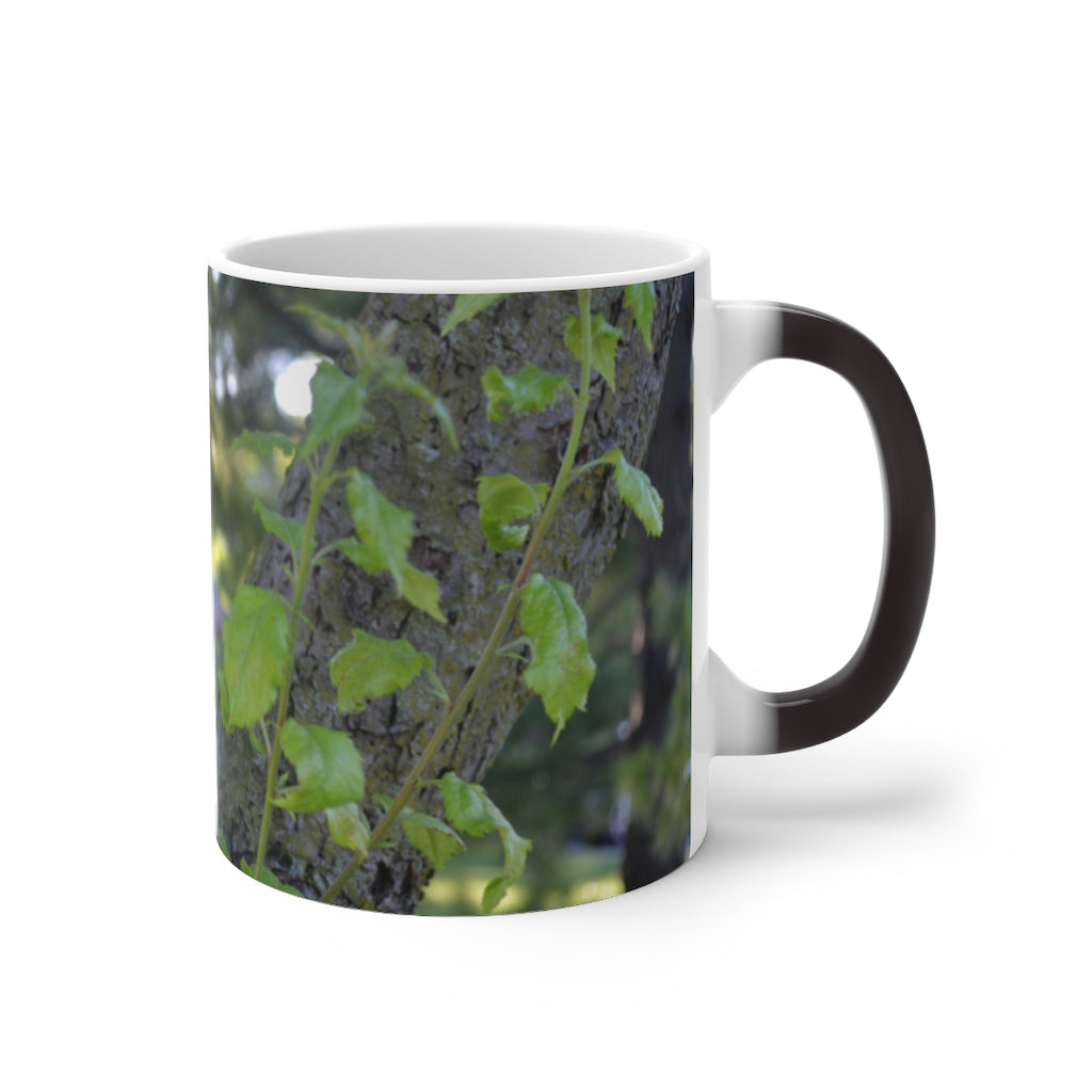 A color-changing ceramic mug featuring a tree stump and green leaves design, showcasing its vibrant colors when filled with hot liquid.
