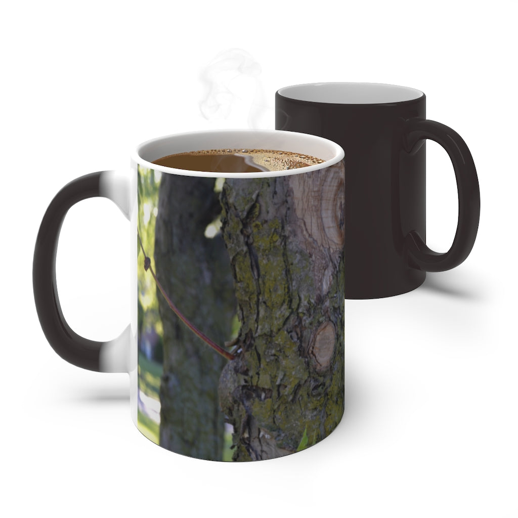 A color-changing ceramic mug featuring a tree stump and green leaves design, showcasing its vibrant colors when filled with hot liquid.