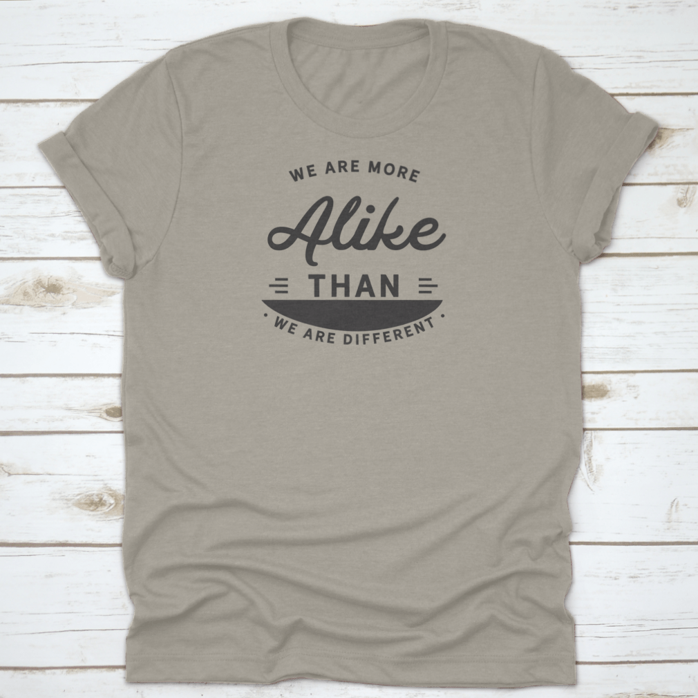 A motivational t-shirt featuring the phrase 'We Are More Alike Than We Are Different', made from soft cotton fabric.