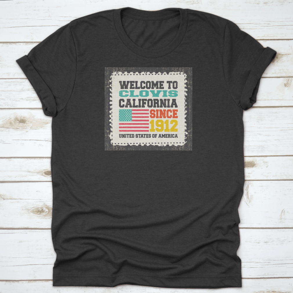A classic fit t-shirt featuring the American flag and the text 'Welcome To Clovis State California Since 1912', made from 100% cotton.