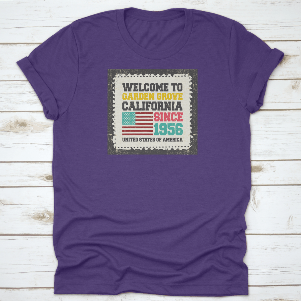 A classic t-shirt featuring the American flag and the text 'Welcome To Garden Grove, California' since 1956, showcasing a vibrant design.
