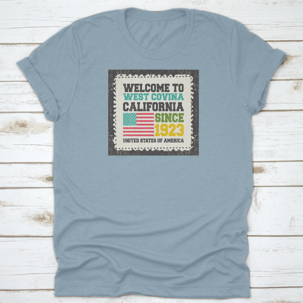 A classic t-shirt featuring the American flag and the text 'Welcome To West Covina State California Since 1923', showcasing pride for the city.