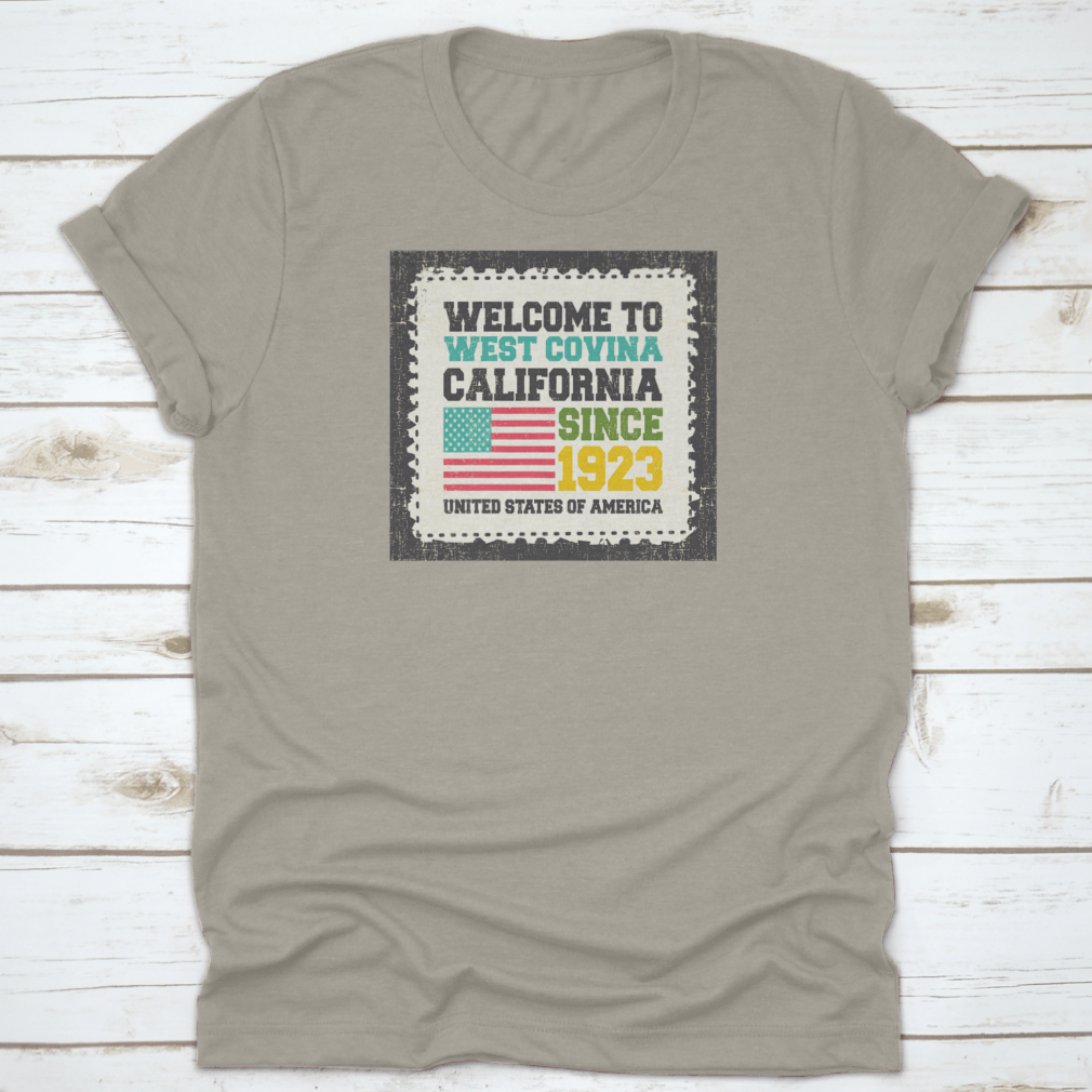 A classic t-shirt featuring the American flag and the text 'Welcome To West Covina State California Since 1923', showcasing pride for the city.