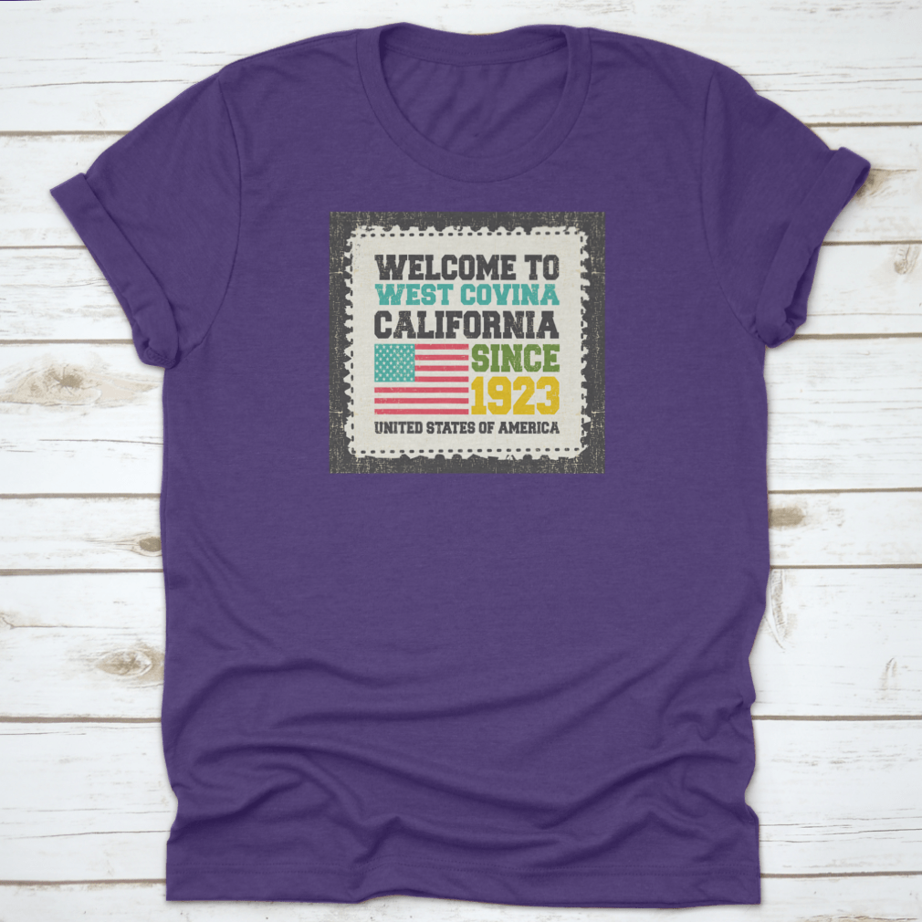 A classic t-shirt featuring the American flag and the text 'Welcome To West Covina State California Since 1923', showcasing pride for the city.