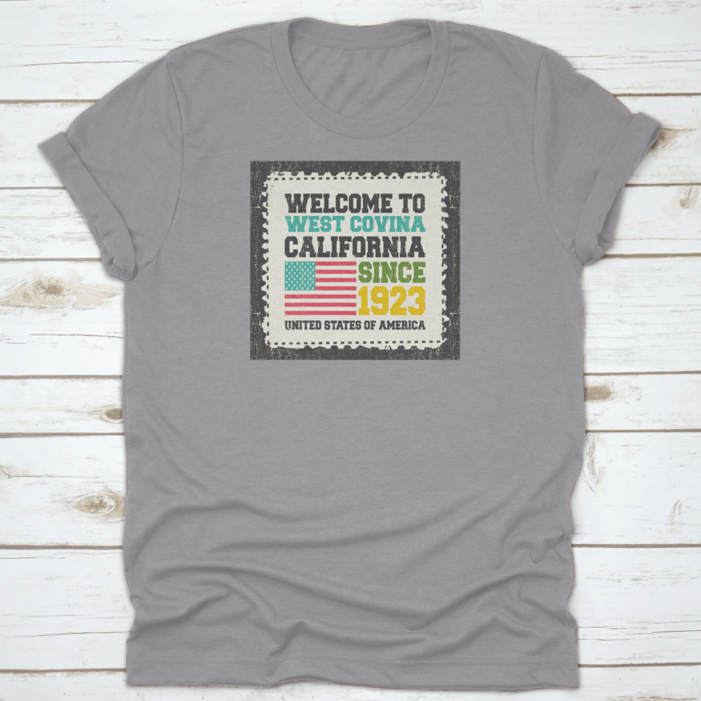 A classic t-shirt featuring the American flag and the text 'Welcome To West Covina State California Since 1923', showcasing pride for the city.