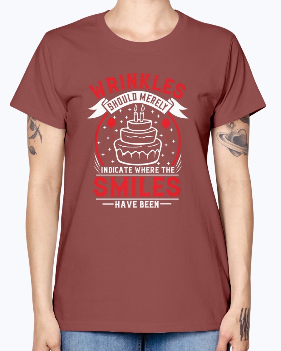 A stylish women's t-shirt featuring the quote 'Wrinkles should merely indicate where the smiles have been' in a cheerful font, perfect for birthday celebrations.