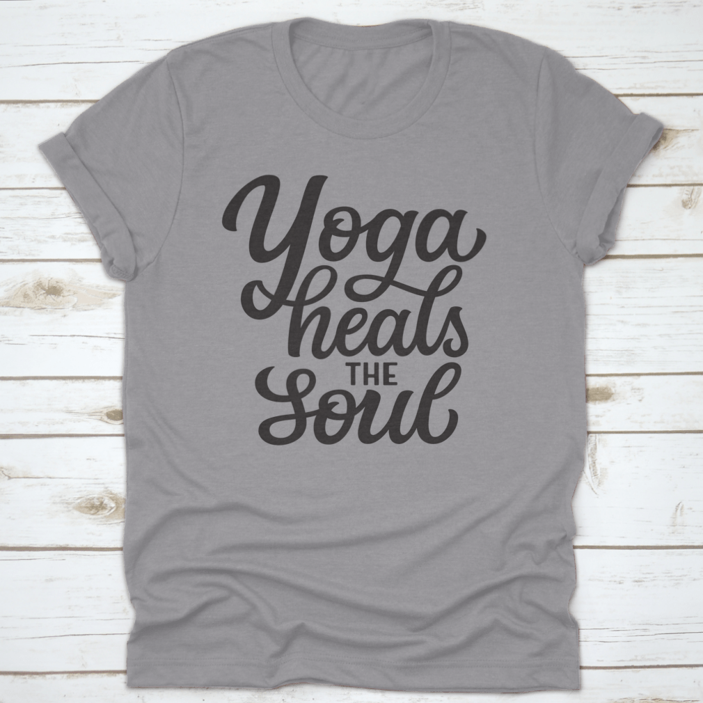A hand-drawn quote 'Yoga Heals The Soul' printed on a white cotton t-shirt, showcasing a stylish and inspirational design.