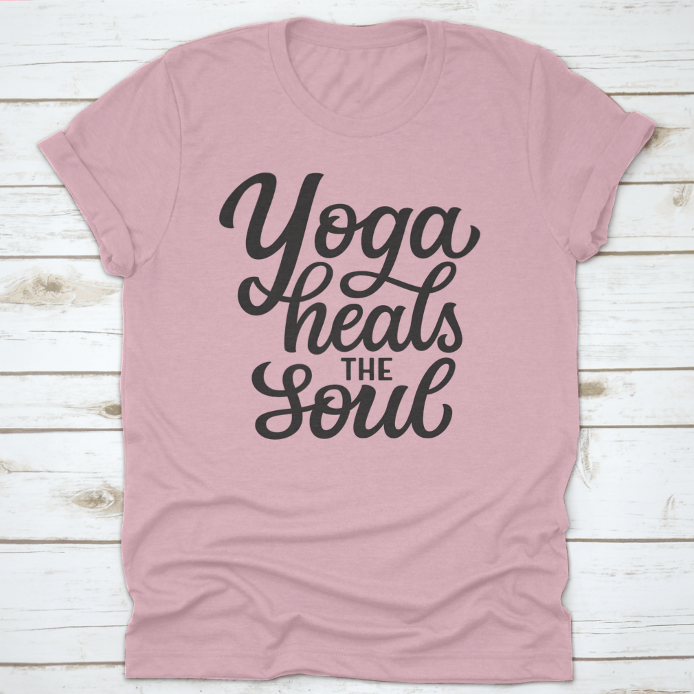 A hand-drawn quote 'Yoga Heals The Soul' printed on a white cotton t-shirt, showcasing a stylish and inspirational design.
