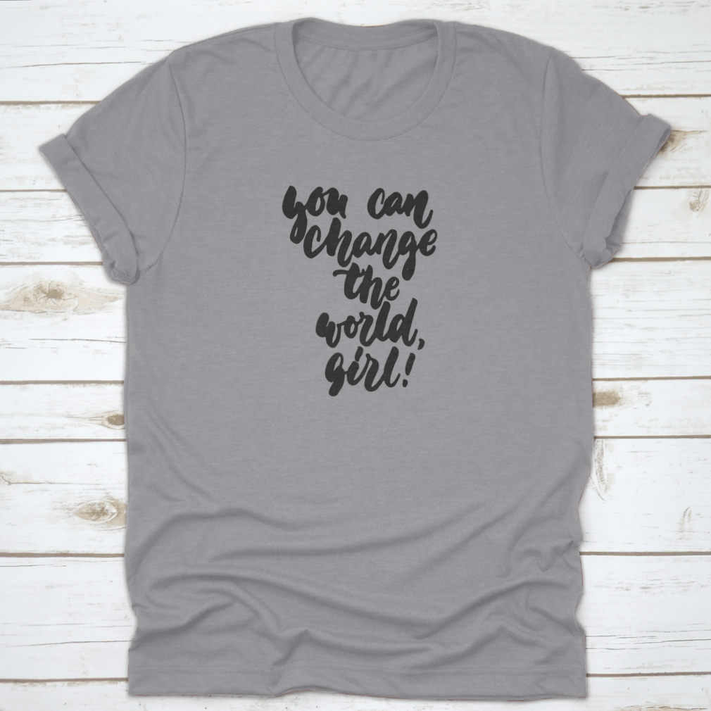 A stylish t-shirt featuring hand-drawn lettering that reads 'You Can Change The World, Girl', made from soft cotton fabric.