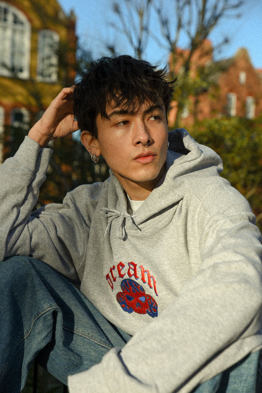 Heather grey unisex hoodie featuring flaming skull embroidery, showcasing a relaxed fit and heavyweight cotton material.