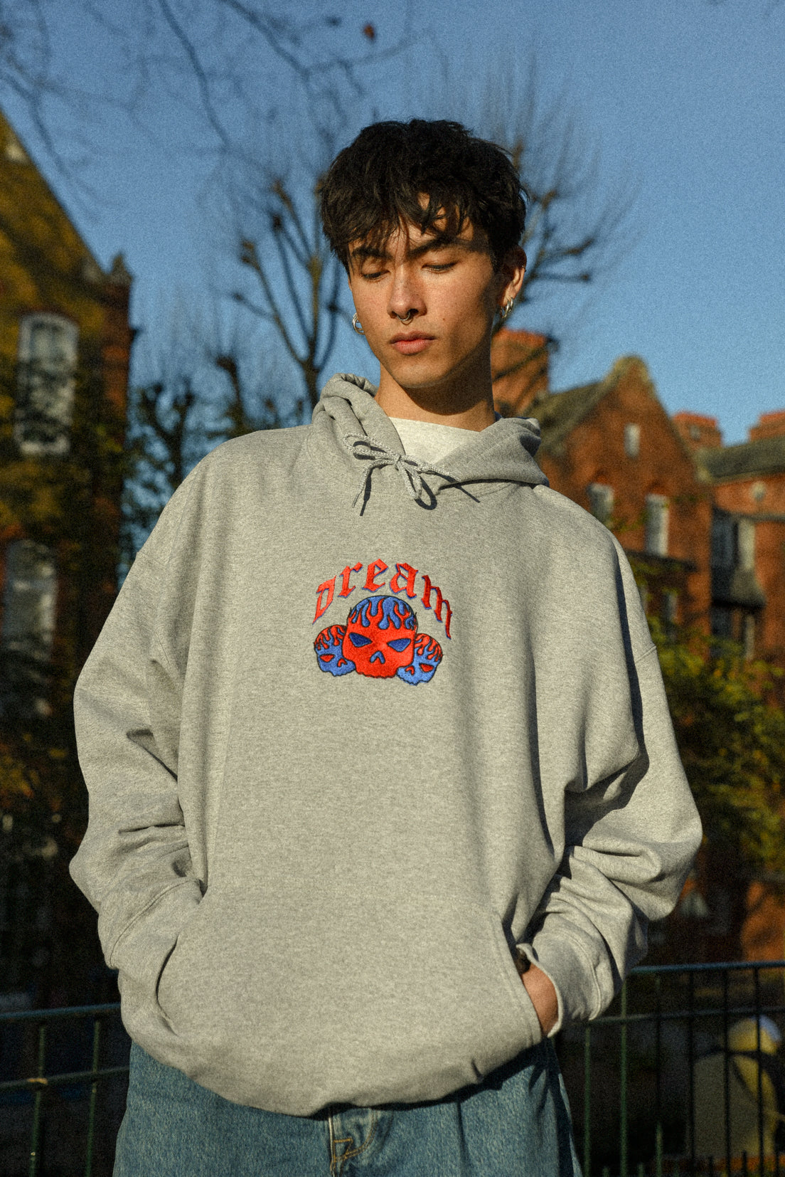 Heather grey unisex hoodie featuring flaming skull embroidery, showcasing a relaxed fit and heavyweight cotton material.