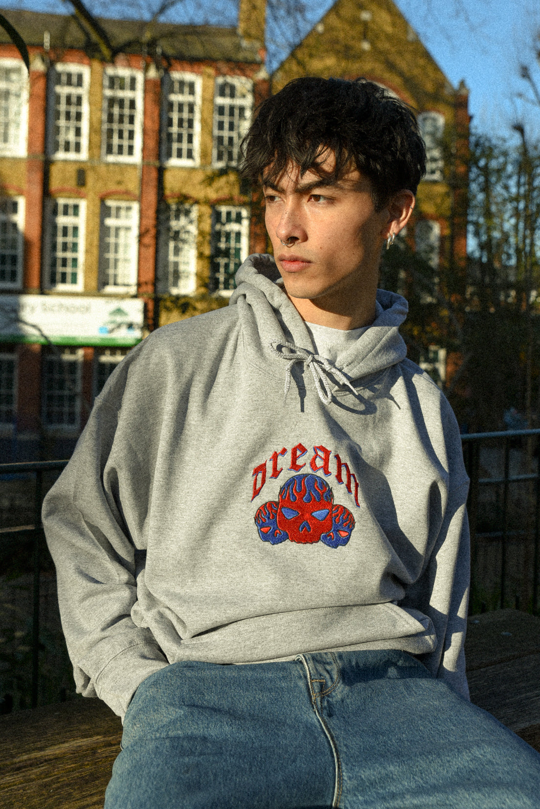 Heather grey unisex hoodie featuring flaming skull embroidery, showcasing a relaxed fit and heavyweight cotton material.