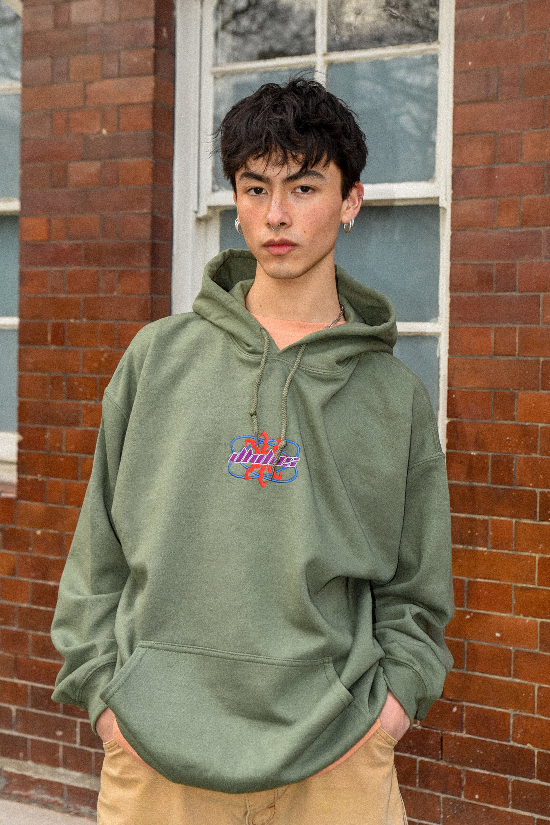 Military green unisex hoodie with futuristic logo embroidery, showcasing a relaxed fit and heavyweight cotton material.