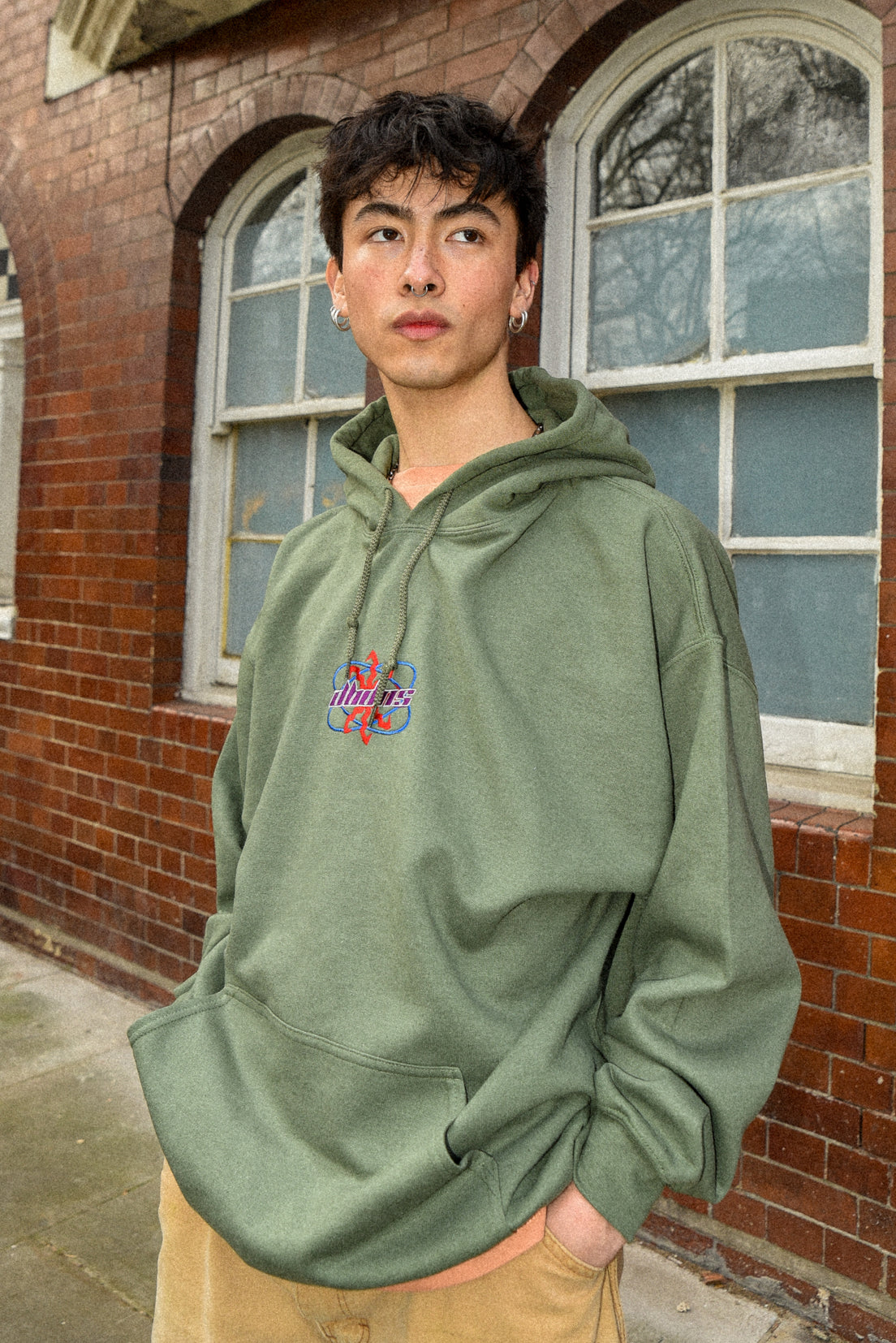 Military green unisex hoodie with futuristic logo embroidery, showcasing a relaxed fit and heavyweight cotton material.