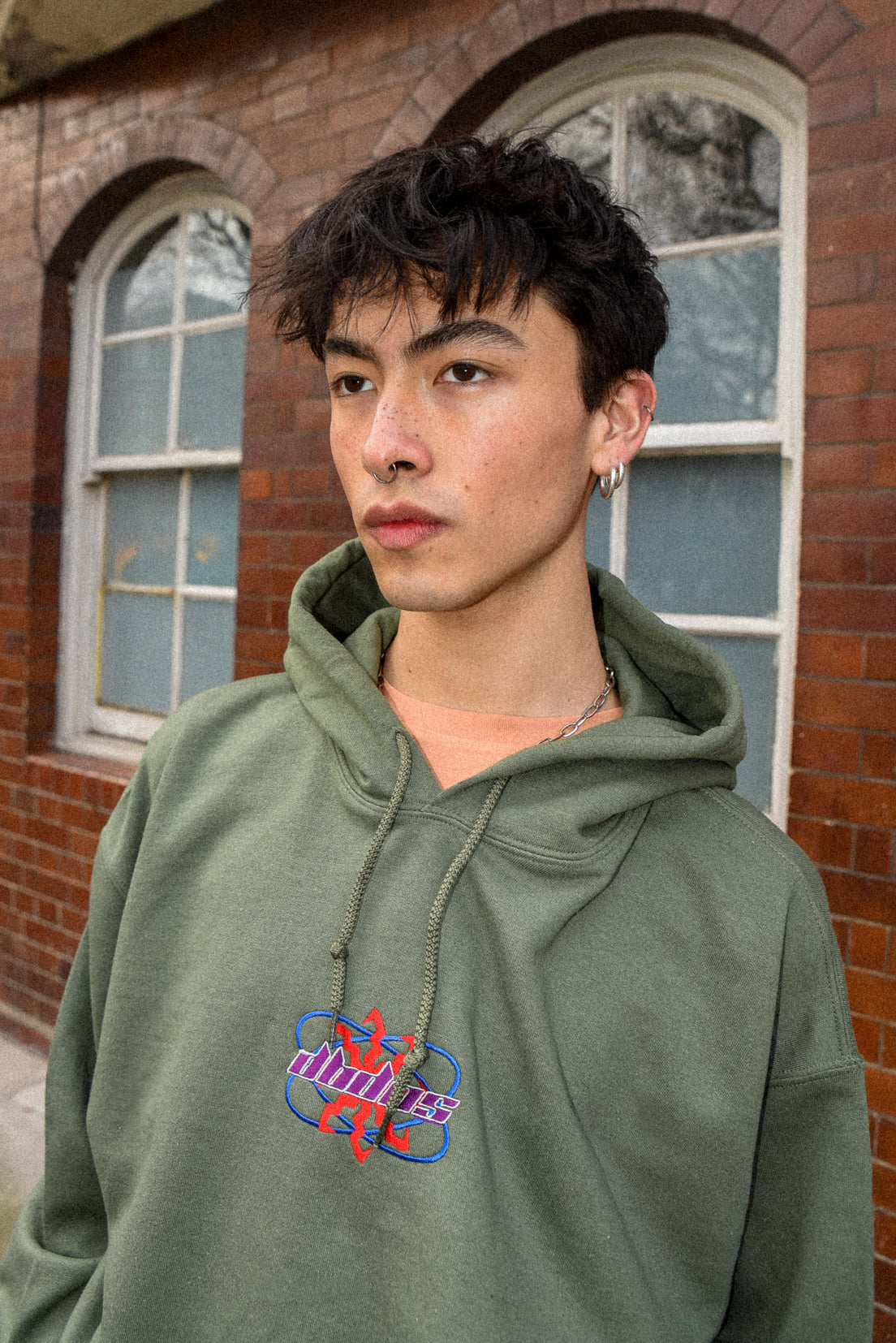 Military green unisex hoodie with futuristic logo embroidery, showcasing a relaxed fit and heavyweight cotton material.