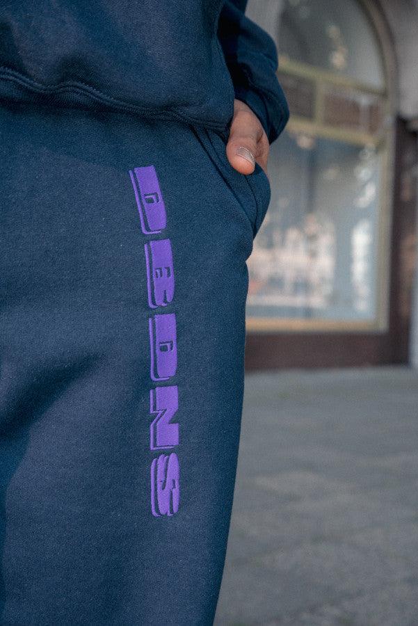 Navy joggers with purple embroidered logo, showcasing a relaxed fit and soft fabric, ideal for summer lounging.