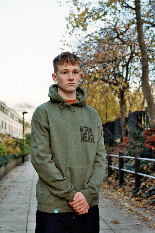 Military green hoodie featuring 'The End Is Near' printed design on the front, showcasing a relaxed fit and woven label details.
