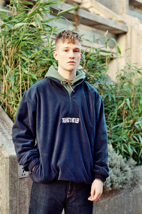 Navy blue fleece sweatshirt featuring 'Dream But Do Not Sleep' embroidered design on the front, showcasing cozy fleece material and relaxed fit.