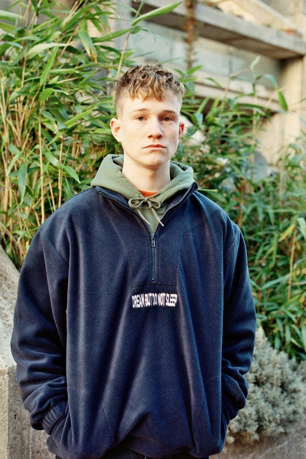 Navy blue fleece sweatshirt featuring 'Dream But Do Not Sleep' embroidered design on the front, showcasing cozy fleece material and relaxed fit.