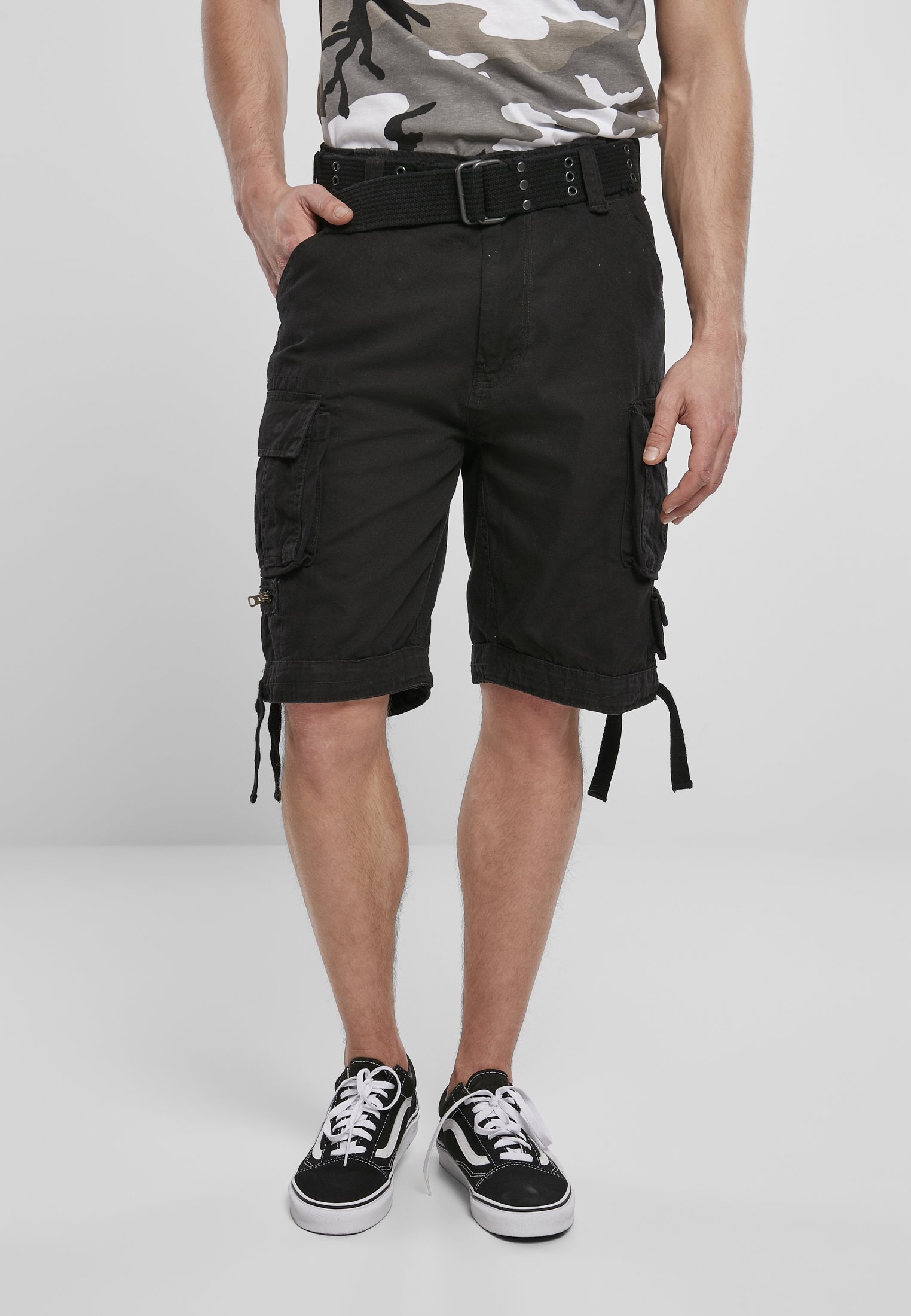 Savage Vintage Cargo Shorts in a rugged outdoor setting, showcasing large side pockets and decorative belt with eyelets.