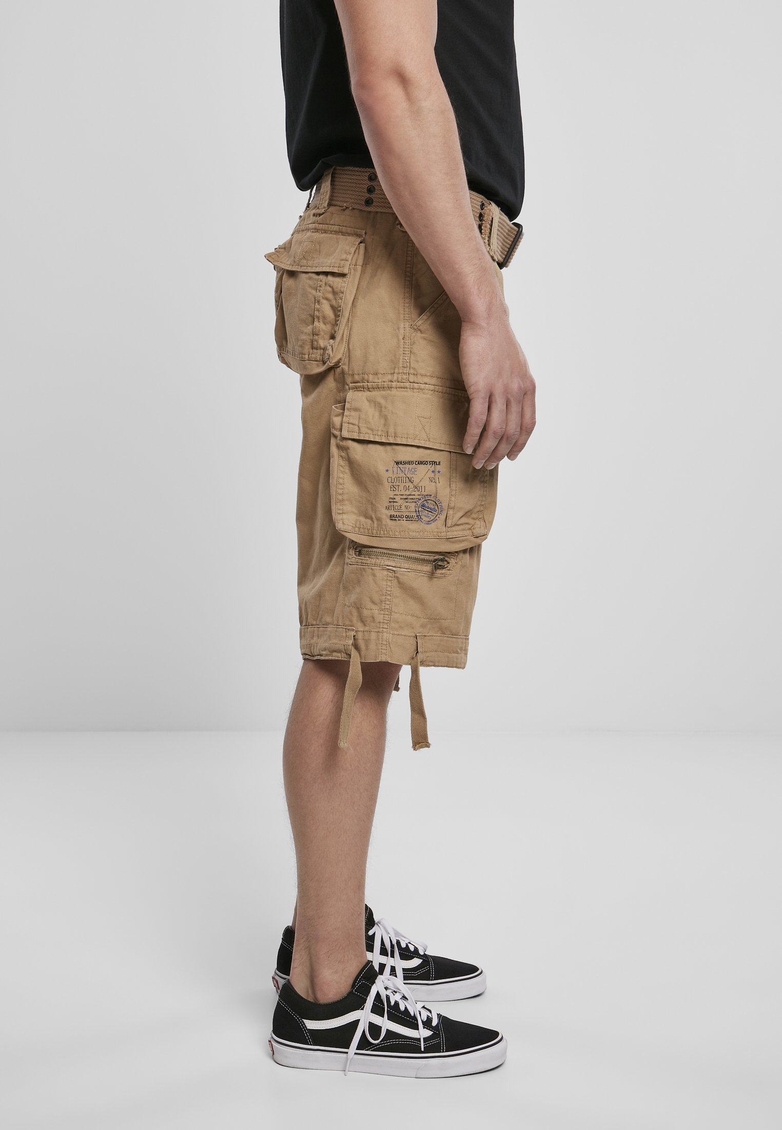 Savage Vintage Cargo Shorts in a rugged outdoor setting, showcasing large side pockets and decorative belt with eyelets.