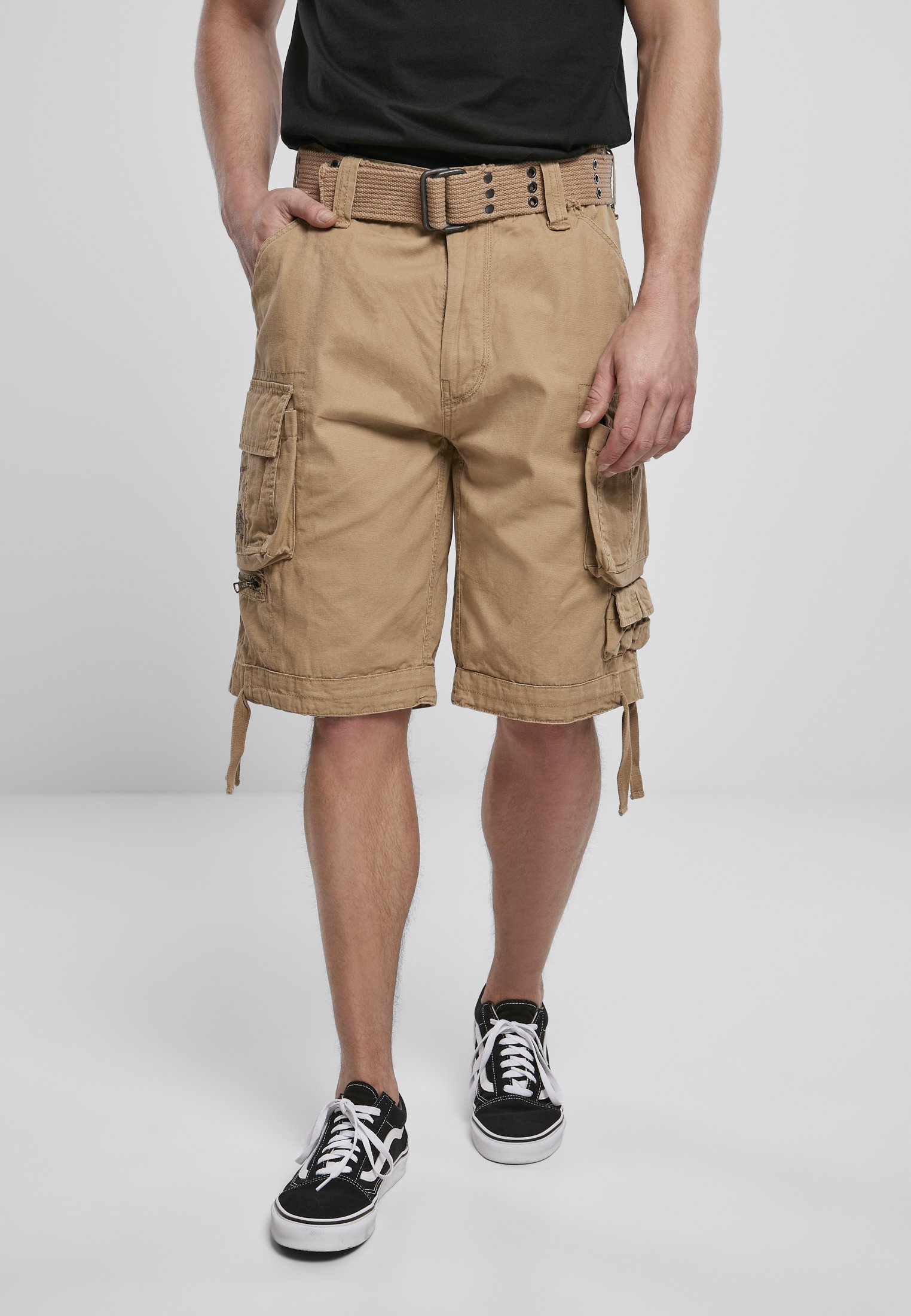 Savage Vintage Cargo Shorts in a rugged outdoor setting, showcasing large side pockets and decorative belt with eyelets.