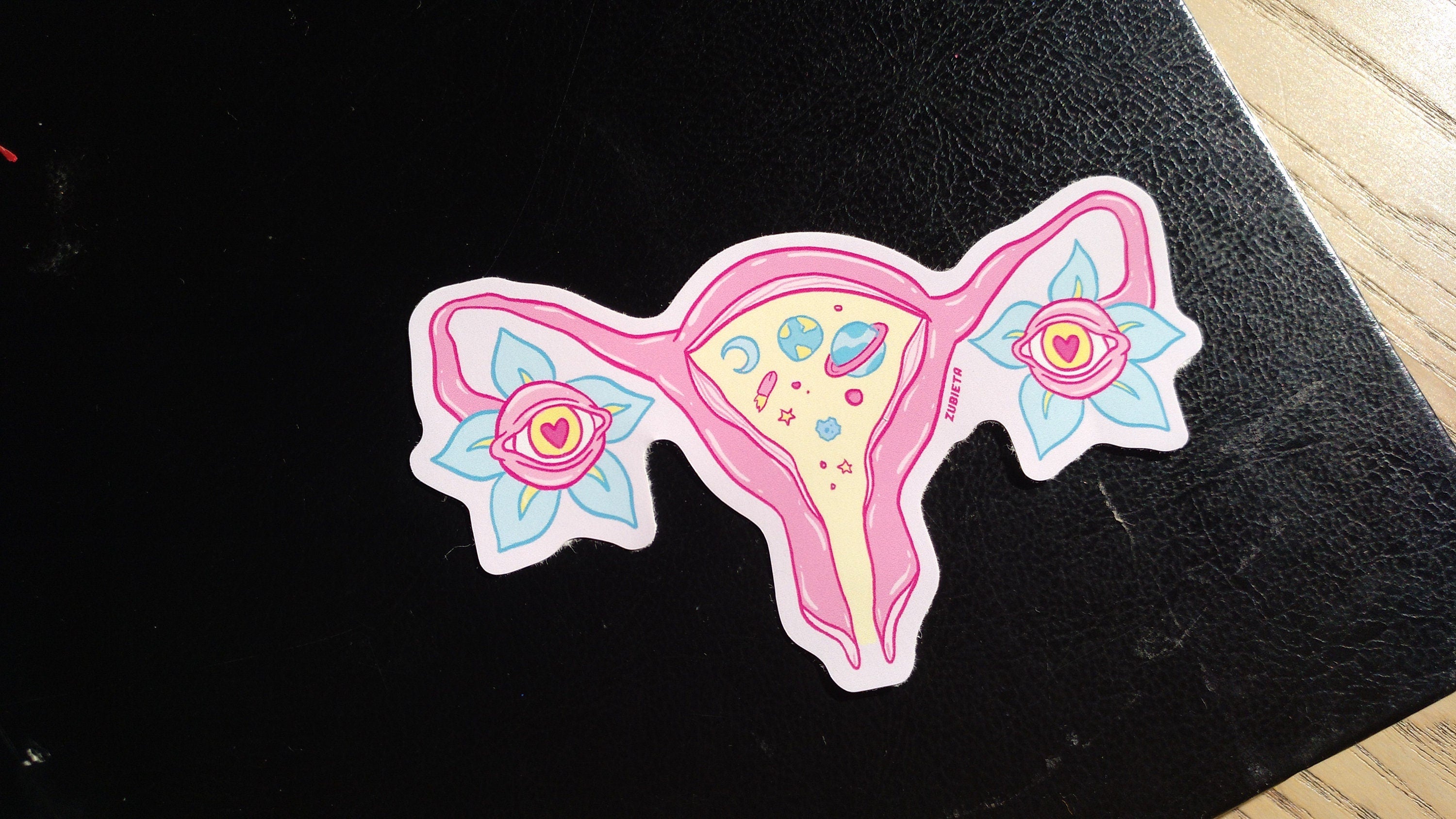 A vibrant Cosmic Uterus Sticker featuring intricate designs, perfect for personalizing laptops, notebooks, and cars.