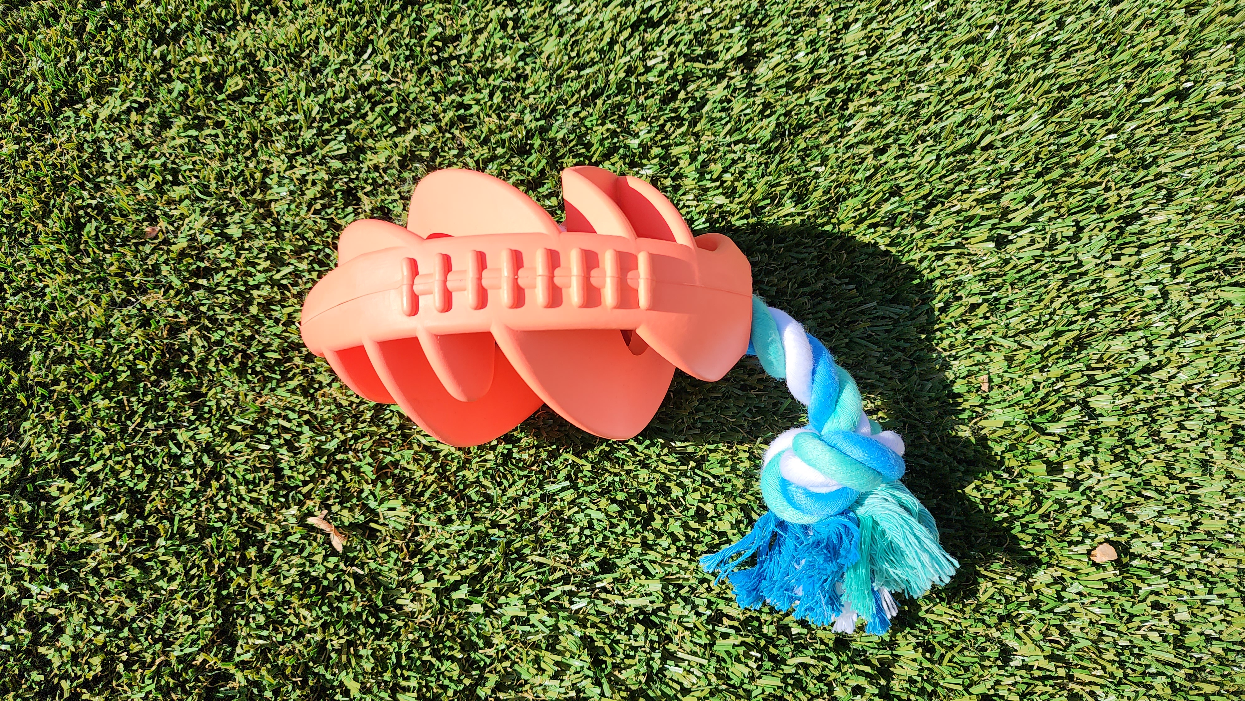 Rubber football dog chew toy with a durable tug rope, designed for active dogs of various sizes, showcasing its bright colors and robust construction.